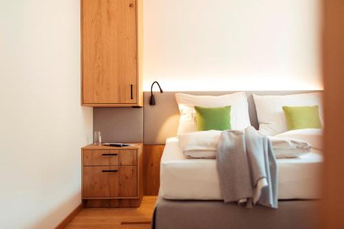 菲伯布伦All-Suite Resort Fieberbrunn inklusive Gästekarte & Lauchsee-Eintritt的卧室里有一张床，上面有绿色和白色的枕头