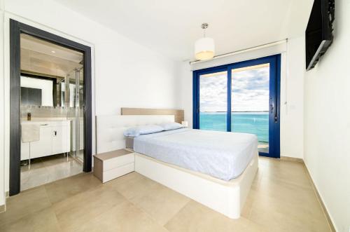 a white bedroom with a bed and a large window at Bennecke Velvet in Punta Prima