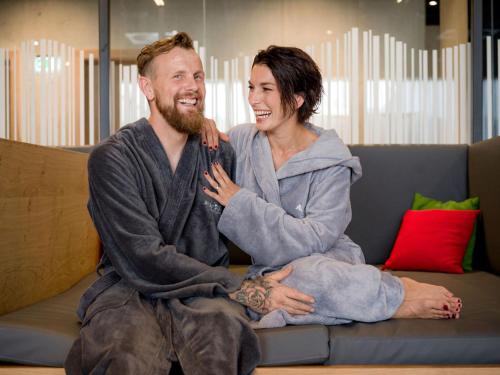 a man and a woman sitting on a couch at All-Suite Resort Fieberbrunn inklusive Gästekarte & Aubad-Eintritt in Fieberbrunn