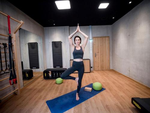 a woman doing a yoga pose in a gym at All-Suite Resort Fieberbrunn inklusive Gästekarte & Aubad-Eintritt in Fieberbrunn