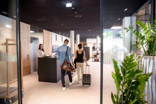 a group of people walking through an office with luggage at All-Suite Resort Fieberbrunn inklusive Gästekarte & Aubad-Eintritt in Fieberbrunn