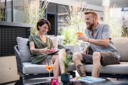 a man and a woman sitting on chairs with drinks at All-Suite Resort Fieberbrunn inklusive Gästekarte & Aubad-Eintritt in Fieberbrunn