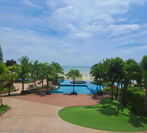 a large swimming pool with palm trees and the ocean at Timurbay Beach Resort Balok Kuantan in Kampung Sungai Karang