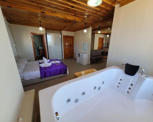 Patara Evleri في باتارا: حوض استحمام كبير في غرفة مع غرفة نوم