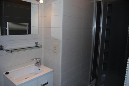 a white bathroom with a sink and a mirror at Gîte La Grange d'Herbuchenne in Dinant