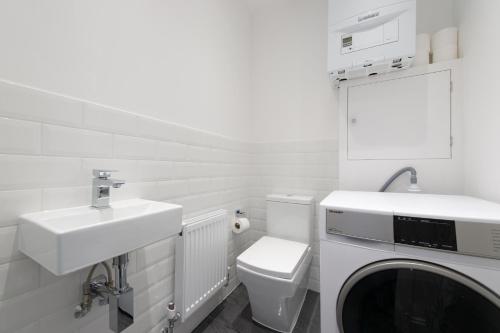 a white bathroom with a sink and a washing machine at Trendy 2 Bed - A hidden Luxury in Hayes nr Heathrow in Hayes