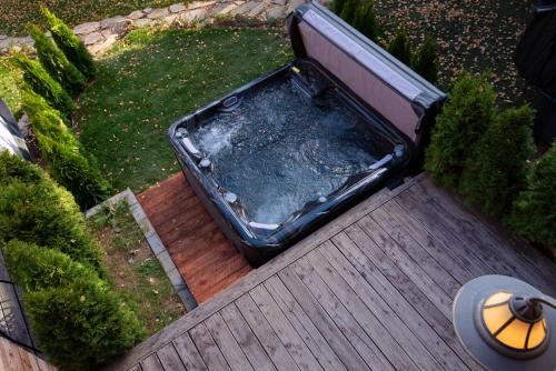 bañera de hidromasaje en la parte superior de una terraza de madera en PinusVillas Conference Lodge, en Zheleznitsa