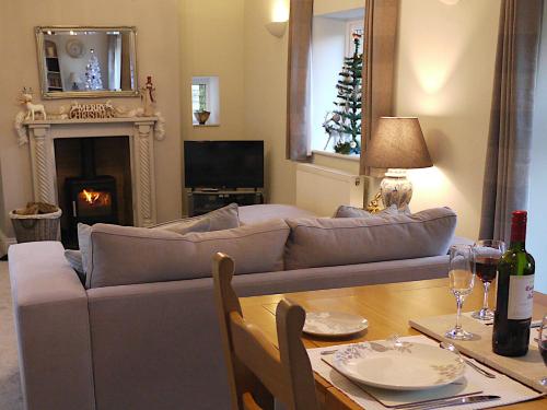 a living room with a couch and a table at Cosy Stone Cottage, The Bungalow Perrotts Brook in Cirencester