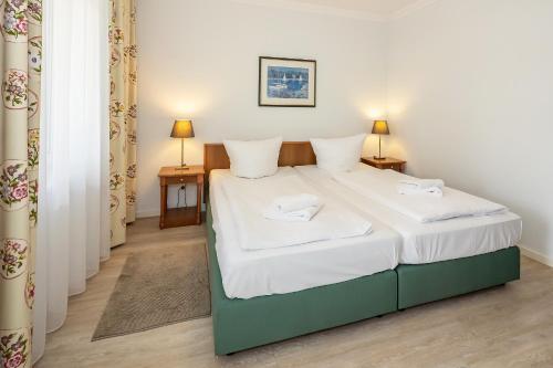 a bedroom with a bed with white sheets and two tables at Seehof Seehof 102 in Bansin