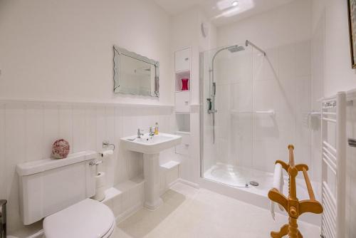 La salle de bains blanche est pourvue d'une douche, de toilettes et d'un lavabo. dans l'établissement 4 Ropers Court Lavenham, à Sudbury