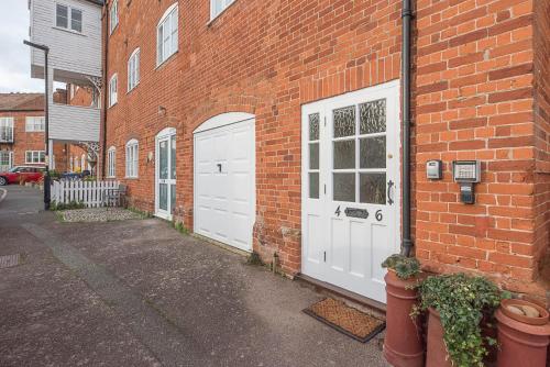 a brick building with two white garage doors on it at 4 Ropers Court, Lavenham in Lavenham