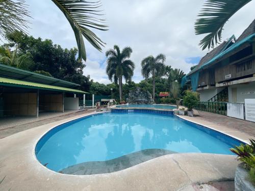 a large blue swimming pool with palm trees in the background at La Virginia Leisure Park and Amusement in Mataasnakahoy
