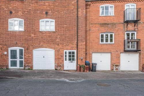 a brick building with four white garage doors at 4 Ropers Court, Lavenham in Lavenham