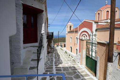 eine Gasse mit einem Gebäude und einer roten Tür in der Unterkunft Fully renovated apartment in the heart of Ioulida on the island of Kea in Ioulis