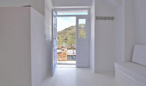 una porta aperta in una camera bianca con vista di Fully renovated apartment in the heart of Ioulida on the island of Kea a Ioulida