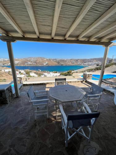 a patio with a table and chairs and a view of the ocean at Yalos Mykonos Ornos Pouli private apartments w shared swimming pool in Mýkonos City