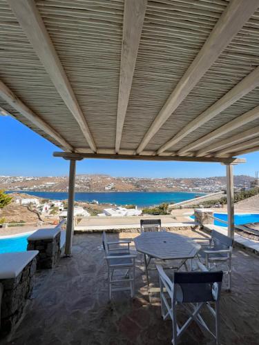 a patio with a table and chairs and a view of the ocean at Yalos Mykonos Ornos Pouli private apartments w shared swimming pool in Mýkonos City