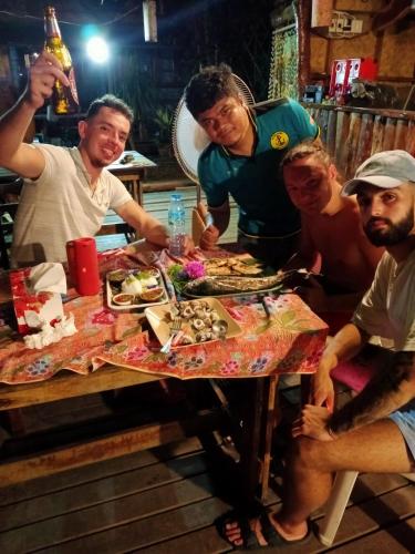 a group of people sitting around a table with food at P P Garden Home Bungalow in Phi Phi Don