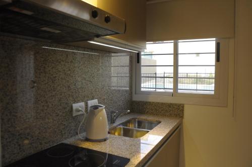 a kitchen counter with a sink and a window at Lom Suites in Merlo