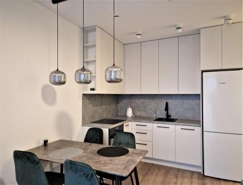 a kitchen with white cabinets and a table and chairs at Aurea apartment in Vilnius