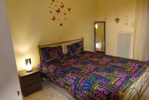 a bedroom with a large bed with a colorful comforter at Black & White Apartment ! in Tríkala