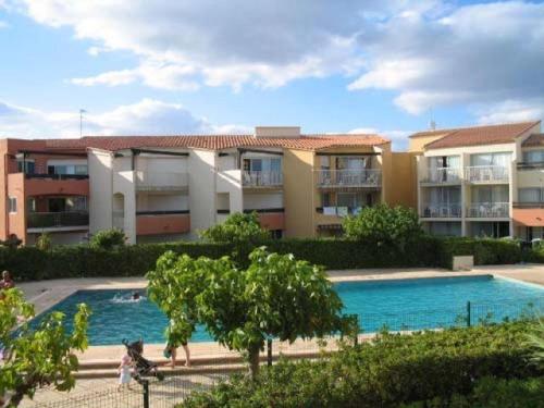 une piscine en face d'un complexe d'appartements dans l'établissement Charmant T2 cabine rénové avec piscine, parking privé, proche plage et commerces - FR-1-607-91, au Cap d'Agde
