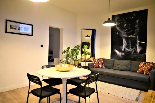 uma sala de estar com uma mesa e cadeiras e um sofá em SLEEP INN - Black and White modern flat with cityview em Antuérpia