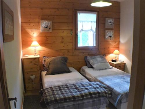 Ce lit se trouve dans un dortoir doté de murs en bois et d'une fenêtre. dans l'établissement Appartement calme et nature sur les hauteurs de Samoëns - Résidence Les Fermes du Villard - FR-1-629-110, à Samoëns