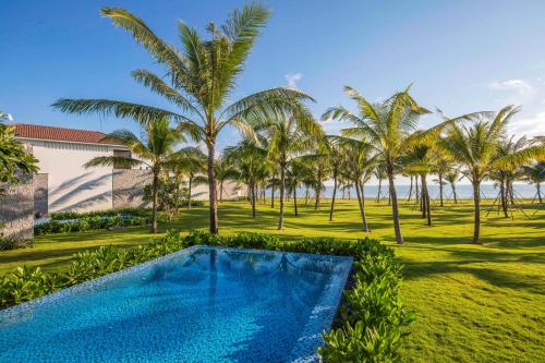 a swimming pool in a yard with palm trees at Vinpearl Resort & Golf Nam Hoi An in Hoi An
