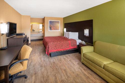 a hotel room with a bed and a desk and couch at Days Inn by Wyndham Tupelo in Tupelo