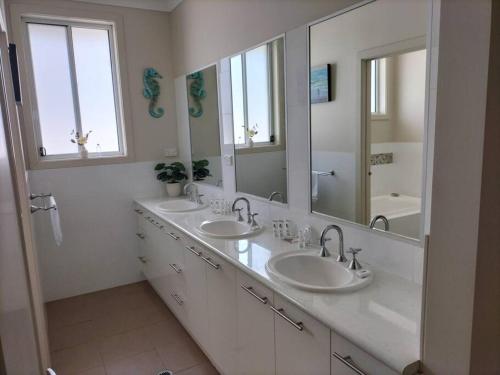 a bathroom with two sinks and two mirrors at Surfmist Barrack Point in Barrack Point