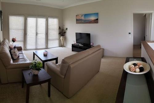 a living room with a couch and a tv at Surfmist Barrack Point in Barrack Point