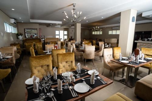 a restaurant with tables and chairs and a chandelier at Tlotlo Hotel & Conference Centre in Gaborone