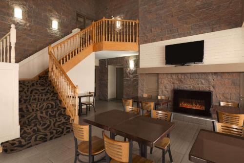 a dining room with a table and a fireplace at Super 8 by Wyndham Timmins ON in Timmins