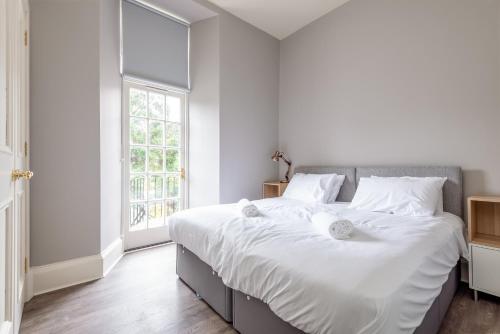 a white bedroom with a large bed and a window at Queen's Gardens Apartment - 2 Bed - Central in St. Andrews