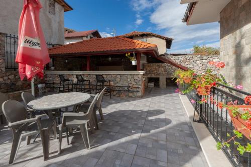 een patio met een tafel en stoelen en een parasol bij Къща за гости Пилигрим in Skrino
