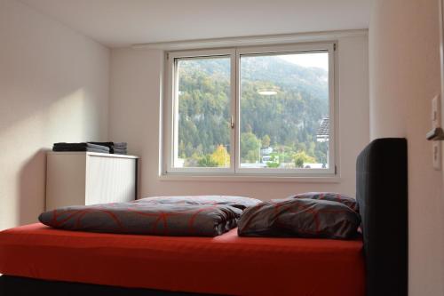 a bed with two pillows in a room with a window at Great new apartment surrounded by nature. in Schattdorf