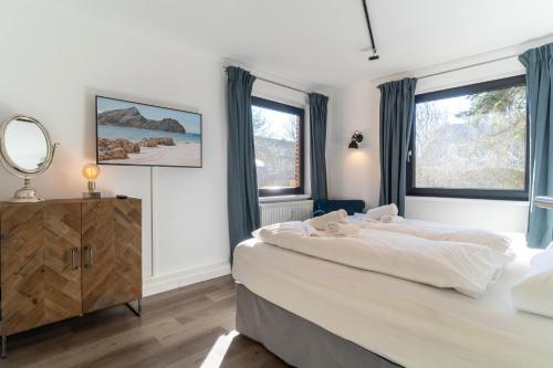 ein Schlafzimmer mit einem großen Bett und zwei Fenstern in der Unterkunft Ankerplatz 1 in Sankt Peter-Ording