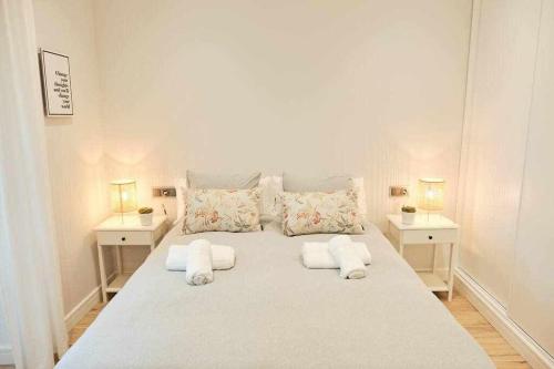 ein großes weißes Bett in einem Zimmer mit 2 Tischen in der Unterkunft CASA ROLAO Elegante Casa Familiar 10 personas in Sierra de Outes