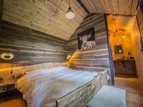 1 dormitorio con 1 cama en una pared de madera en Holiday home 'Be Chalet' in the heart of nature in Ferrieres en Ferrières