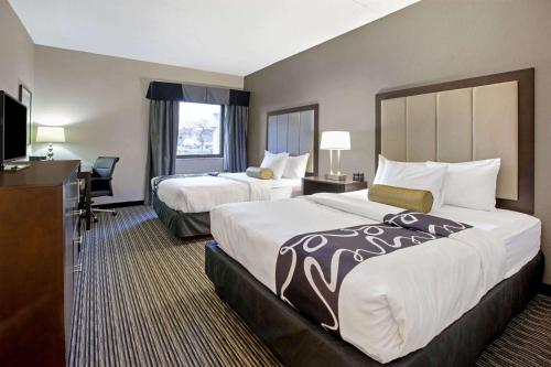 La Quinta Inn & Suites by Wyndham Detroit Metro Airport في رومولوس: غرفه فندقيه سريرين وتلفزيون