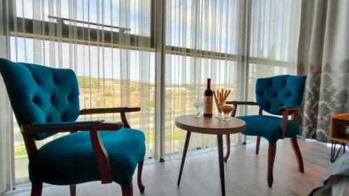 a living room with two chairs and a table and large windows at MİLLS HOTEL in Tekirdag