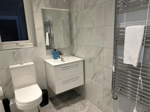 uma casa de banho com um WC, um lavatório e um espelho. em Stunning City Centre Apartments em Cardiff