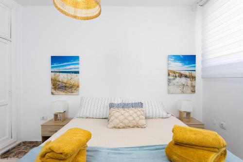 a white bedroom with a bed with yellow pillows at Home2Book Ocean Breeze Candelaria, Terrace & Pool in Candelaria