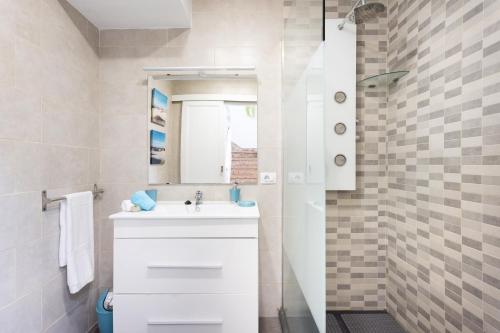 biała łazienka z umywalką i lustrem w obiekcie Home2Book Ocean Breeze Candelaria, Terrace & Pool w mieście Candelaria