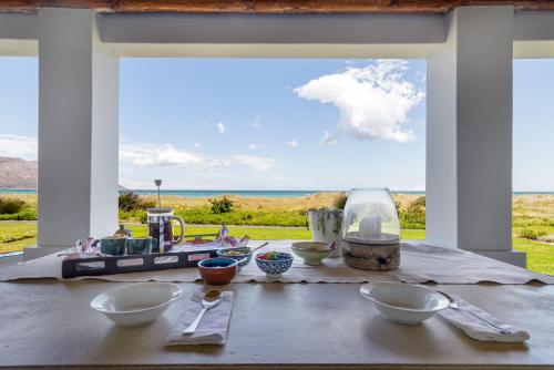 a table with bowls on it with a view of the ocean at Strand Beach Lodge in Strand