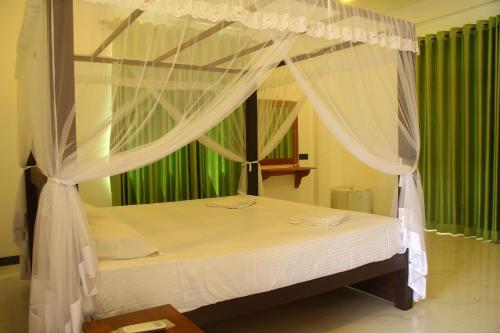 sypialnia z łóżkiem z baldachimem i białymi zasłonami w obiekcie Lihini Beach Villa w mieście Induruwa