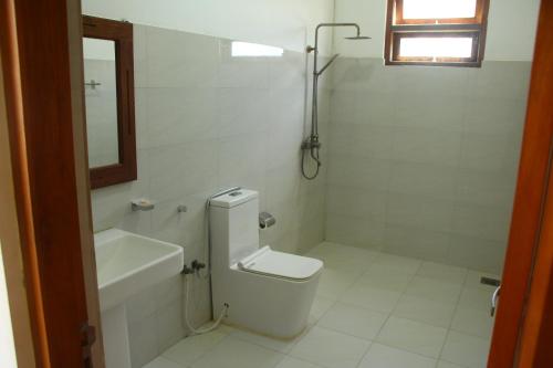 biała łazienka z toaletą i umywalką w obiekcie Lihini Beach Villa w mieście Induruwa