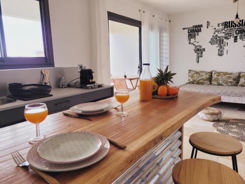 - une cuisine avec une table en bois et 2 verres de jus d'orange dans l'établissement Leu Repère - Location de Charme, à Saint-Leu