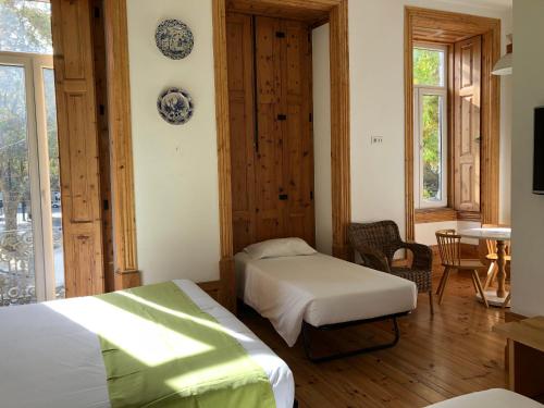 1 dormitorio con 2 camas, mesa y sillas en Casa da Praça Square Suites en Coimbra